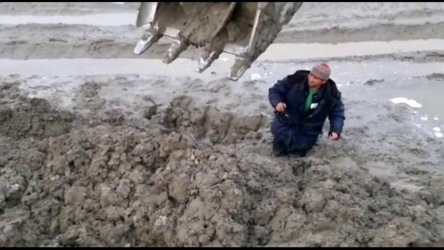 Мужик увяз в грязи и его откапывают экскаватором