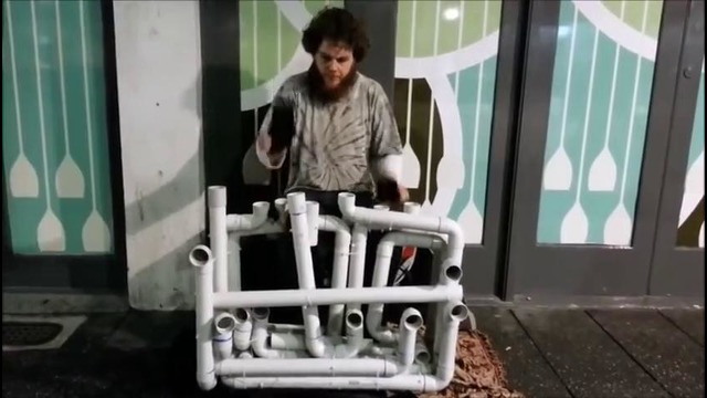 Уличный музыкант играет на водопроводных трубах