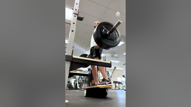 Guy Performs Barbell Workout While Standing on Balance Board