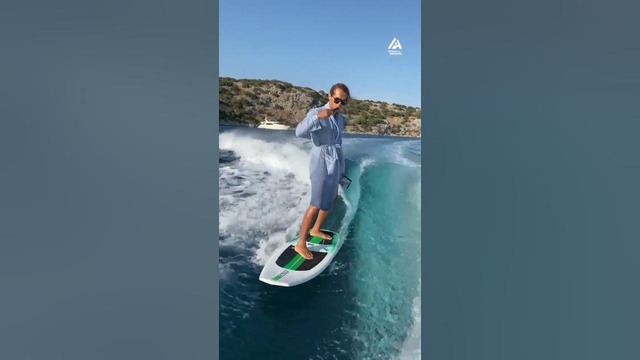 Guy Balances on Surfboard While Multitasking
