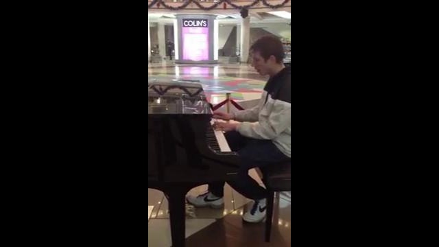 Парень красиво играет в торговом центре на пианино