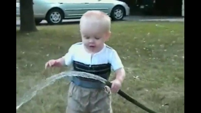 Малыш пытается выпить водички из шланга