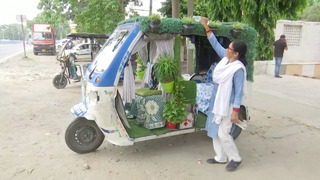 Авторикша с травой на крыше и цветами разъезжает по городу в Индии