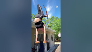 Girl in Handstand Position Fires Arrow at Target Using Toes
