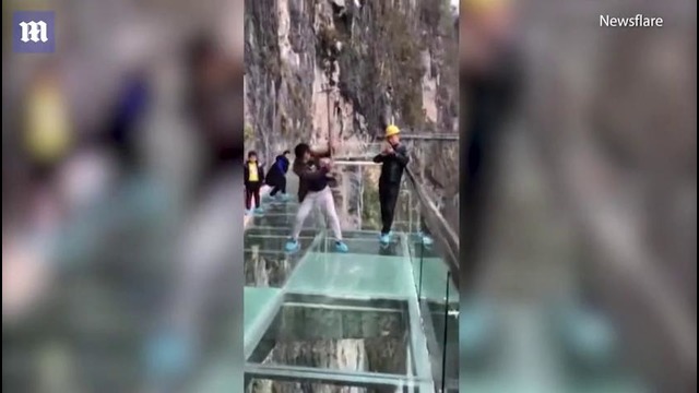 Китайские рабочие проверятют на прочность стеклянный мост