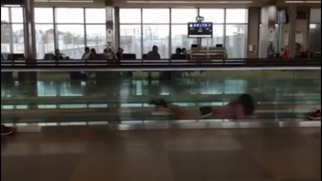 Watch swimming team relieve airport boredom with hilarious stunts on moving walkway