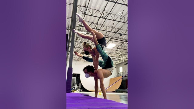 Girl Balances On Guy Performing Handstand And Displays Upside Down Position