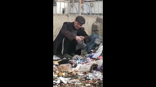 Мужчина на мусорной свалке собирает использованные маски